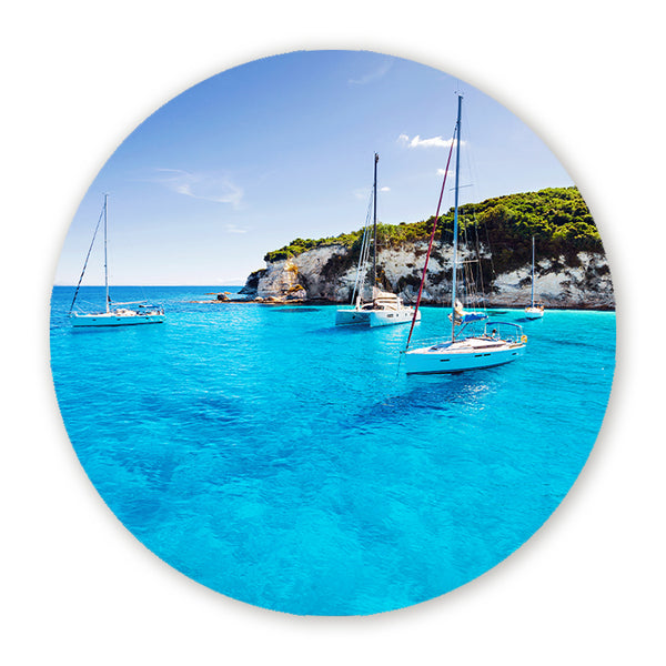 Muurcirkel met zeilboten in een turquoise baai bij een groene rotskust