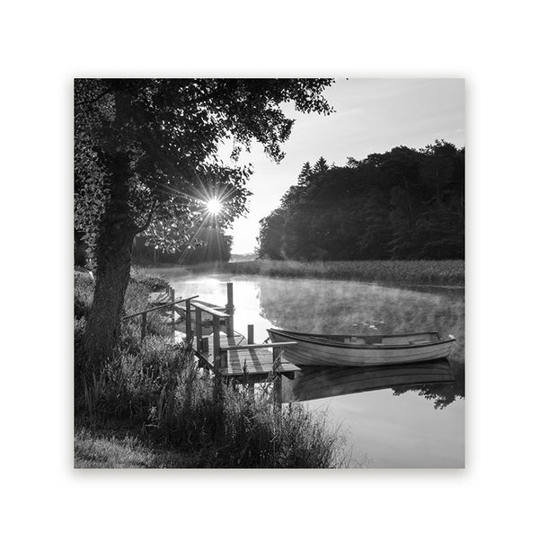 Zwart-wit schilderij van een boot aan een houten steiger op rustig water met zonlicht tussen de bomen